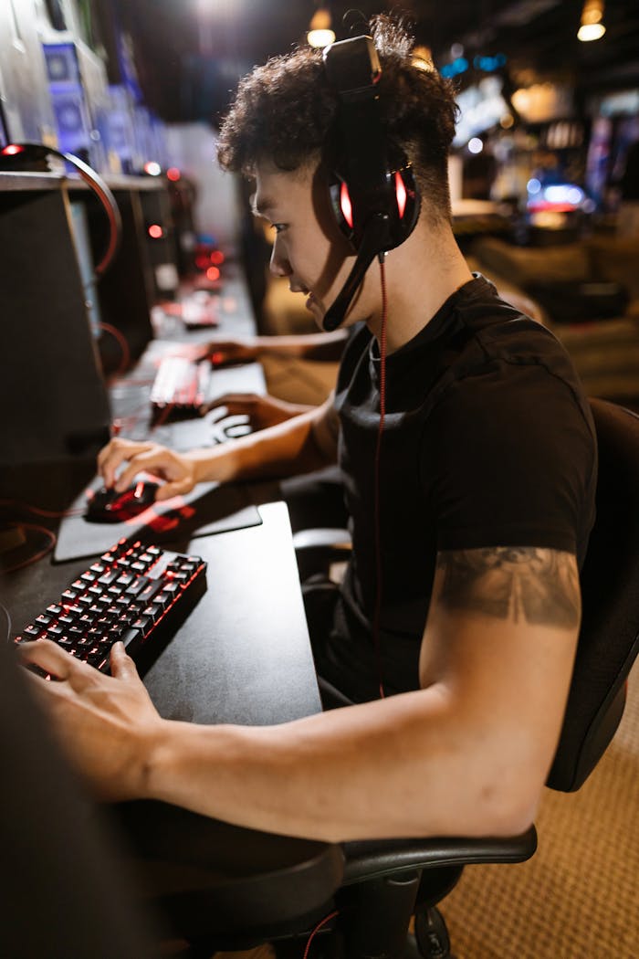 A gamer wearing headphones intensely focused on gaming in a cyber-themed arcade.