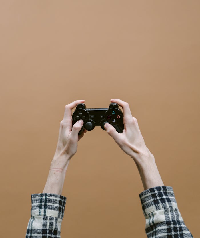 Close-up of hands holding a video game controller against a brown checkered background.